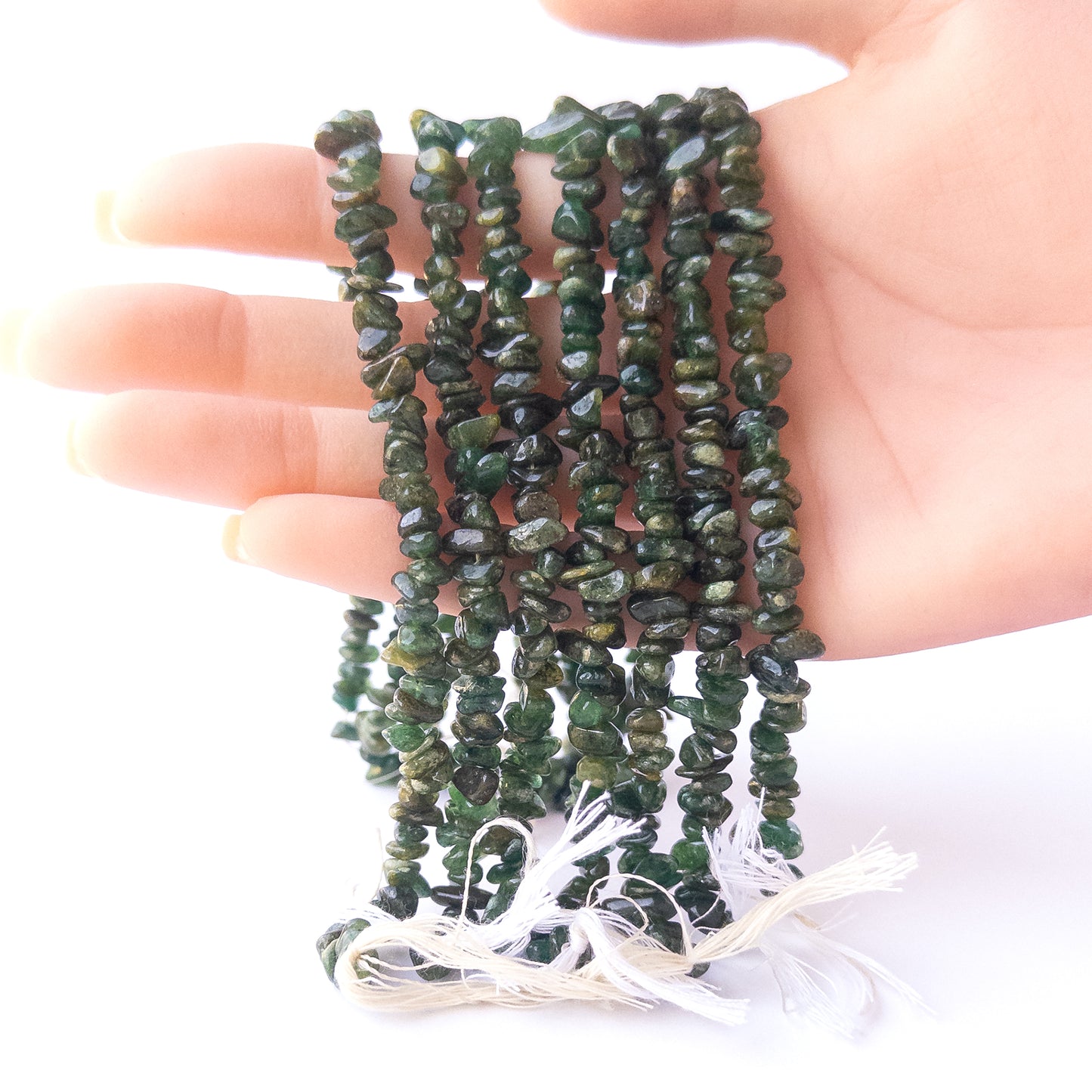 A person holds delicate strands of Aventurine beads, showcasing their chips and nuggets design.