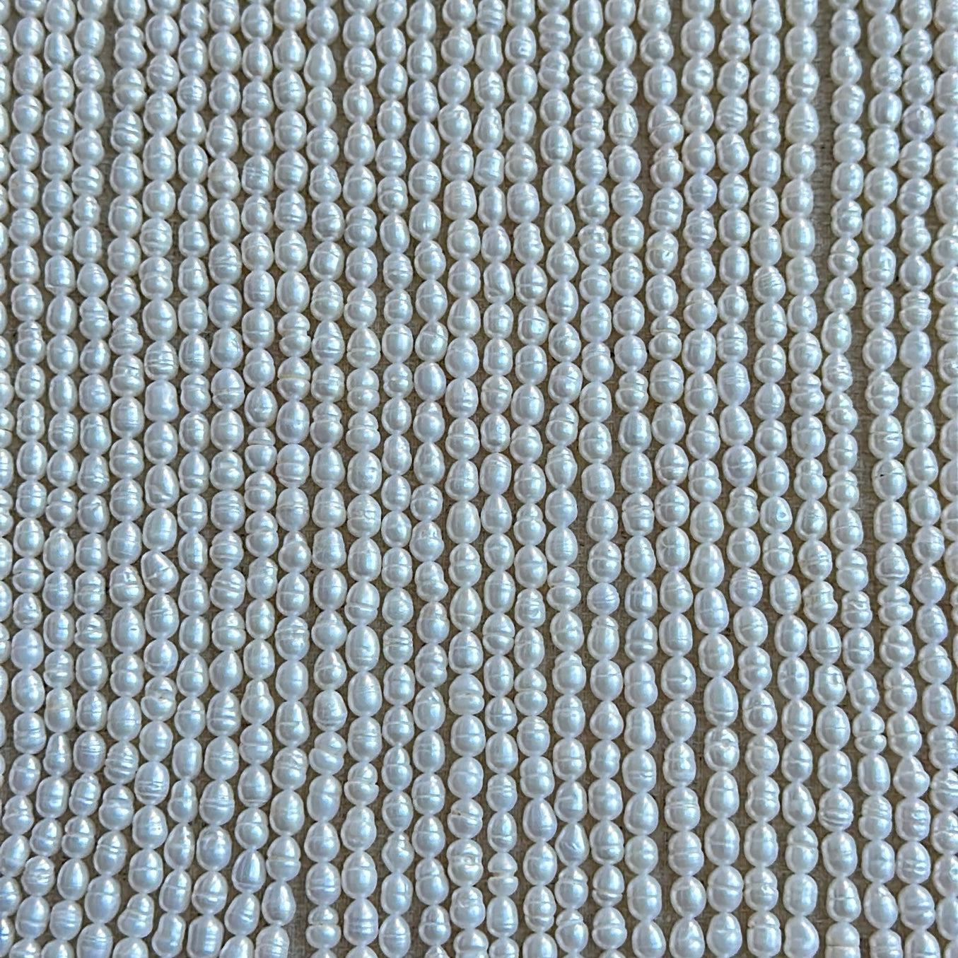 Close-up of Baroque Rice Pearls in creamy white tones with lustrous surface finish and organic rice shape.