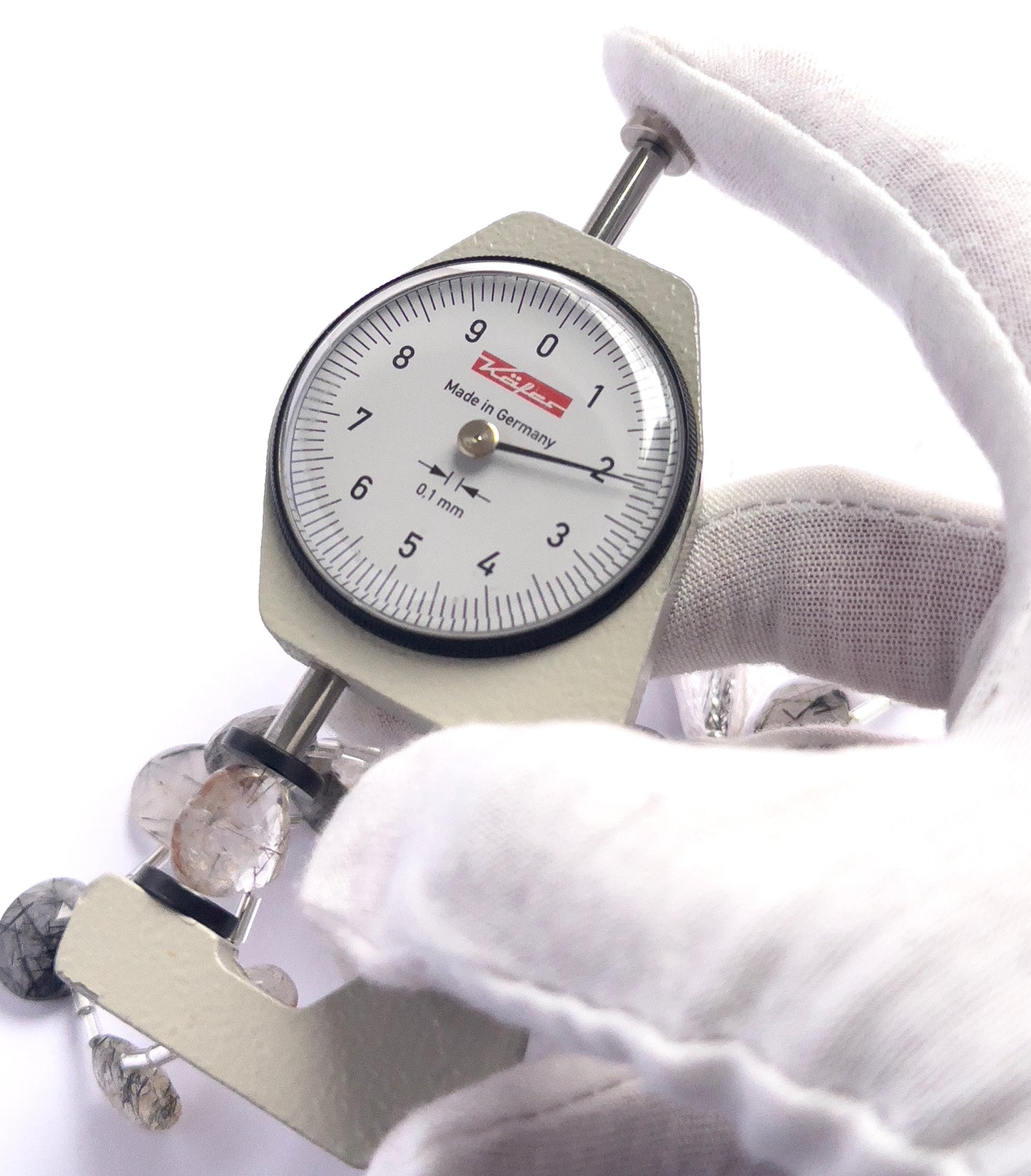 A dial gauge measures the Black Rutile faceted briolette 9.5–12.7mm gemstone.