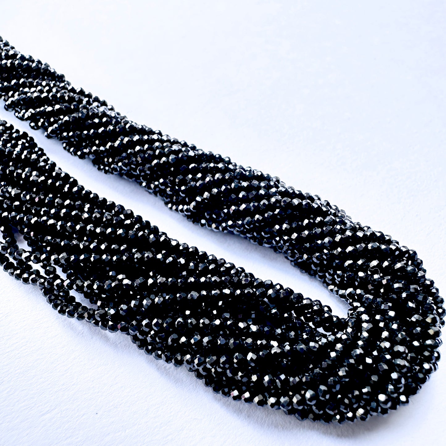 Black Spinel faceted rondelle beads with deep black sparkle arranged on a 32cm strand for jewellery making.