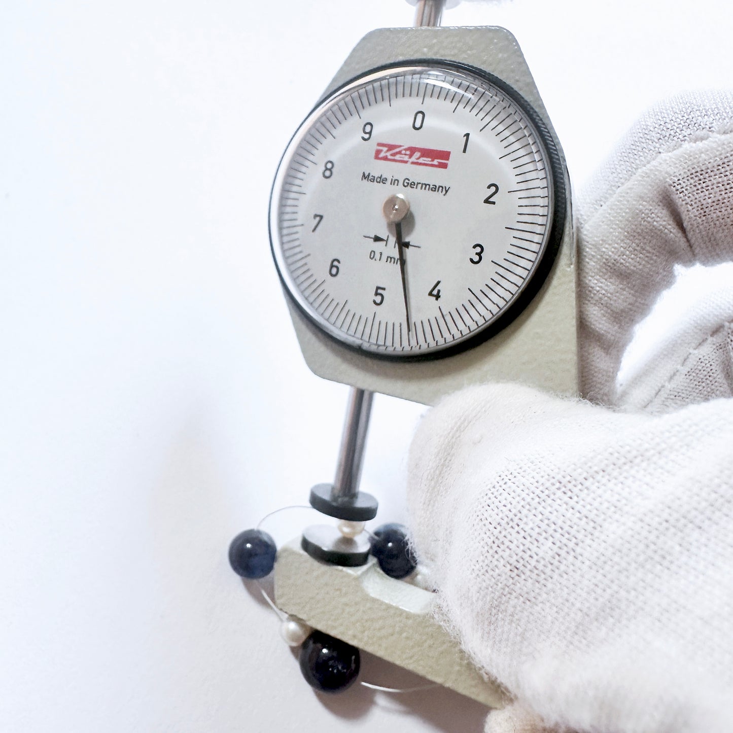 A dial gauge measures the Blue Sapphire smooth round gemstone.