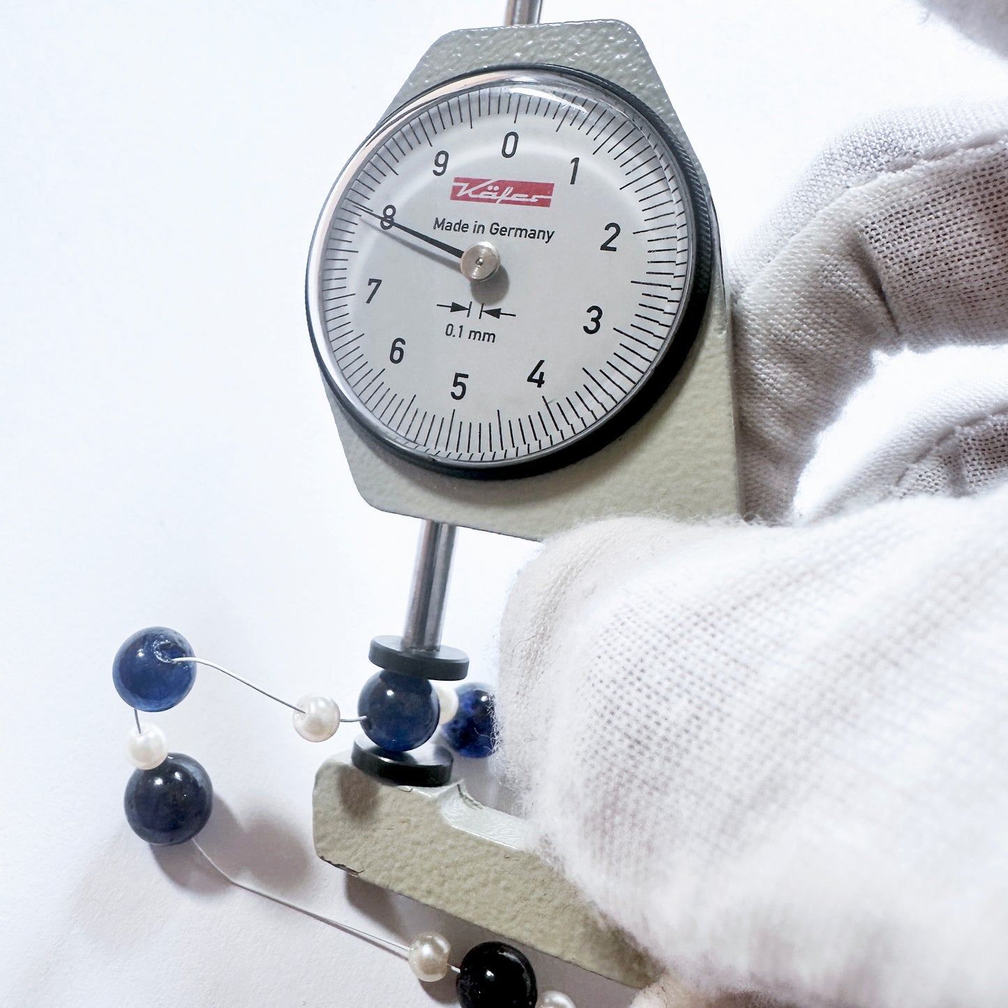 A dial gauge measures the Blue Sapphire smooth round gemstone.