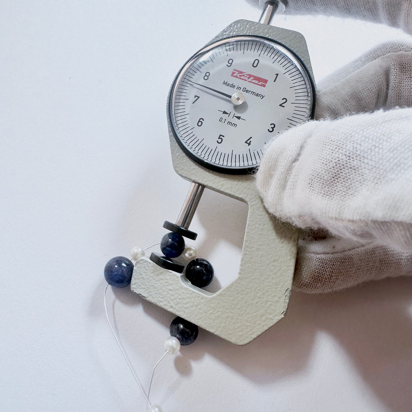 A dial gauge measures the Blue Sapphire smooth round gemstone.