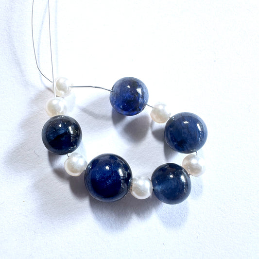 Close-up of natural gemstone beads showing deep blue sapphires and lustrous pearls with polished finish.
