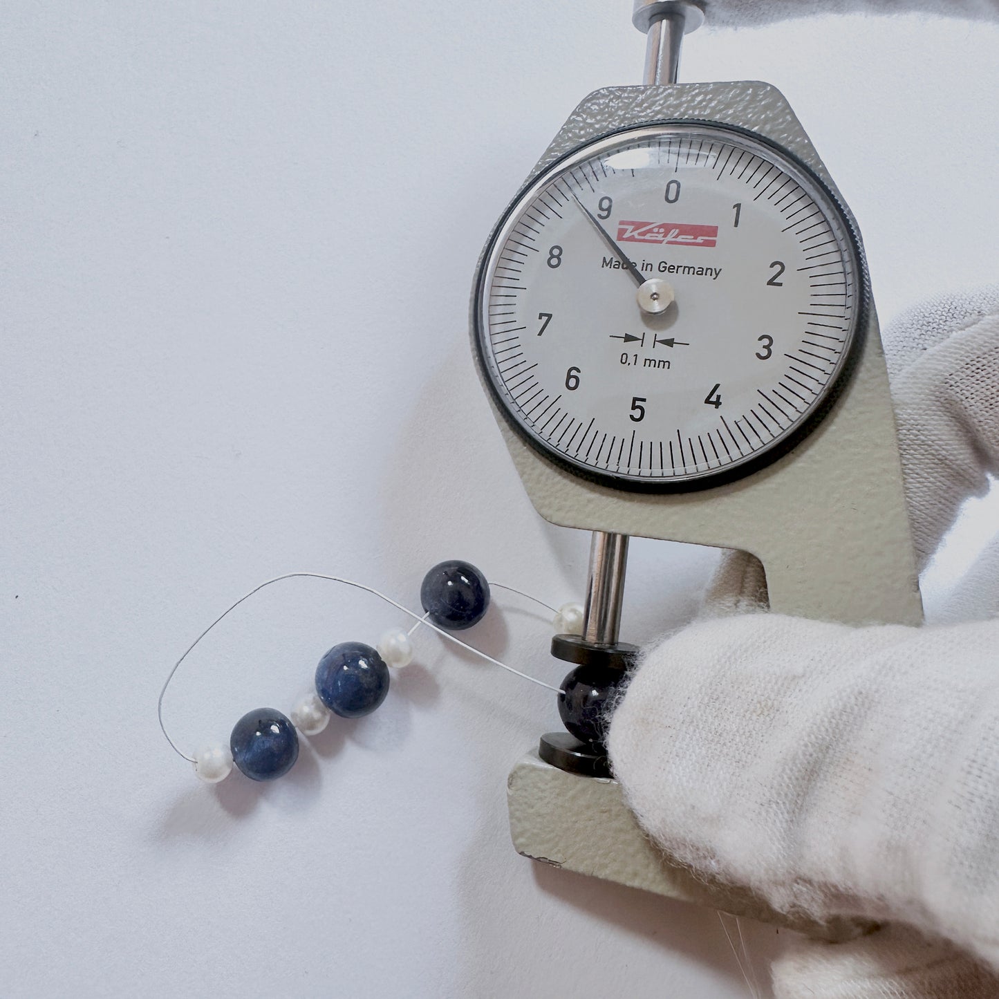 A dial gauge measures the Blue Sapphire smooth round gemstone.