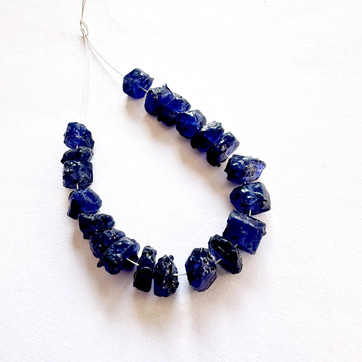 Close-up of rough Blue Sapphire beads with deep blue tones and natural texture.