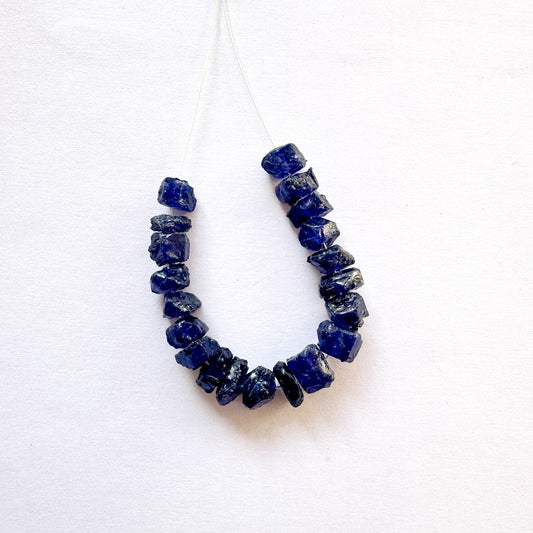 Blue Sapphire 6-8mm beads arranged in a neat strand, highlighting their raw cut and colour.