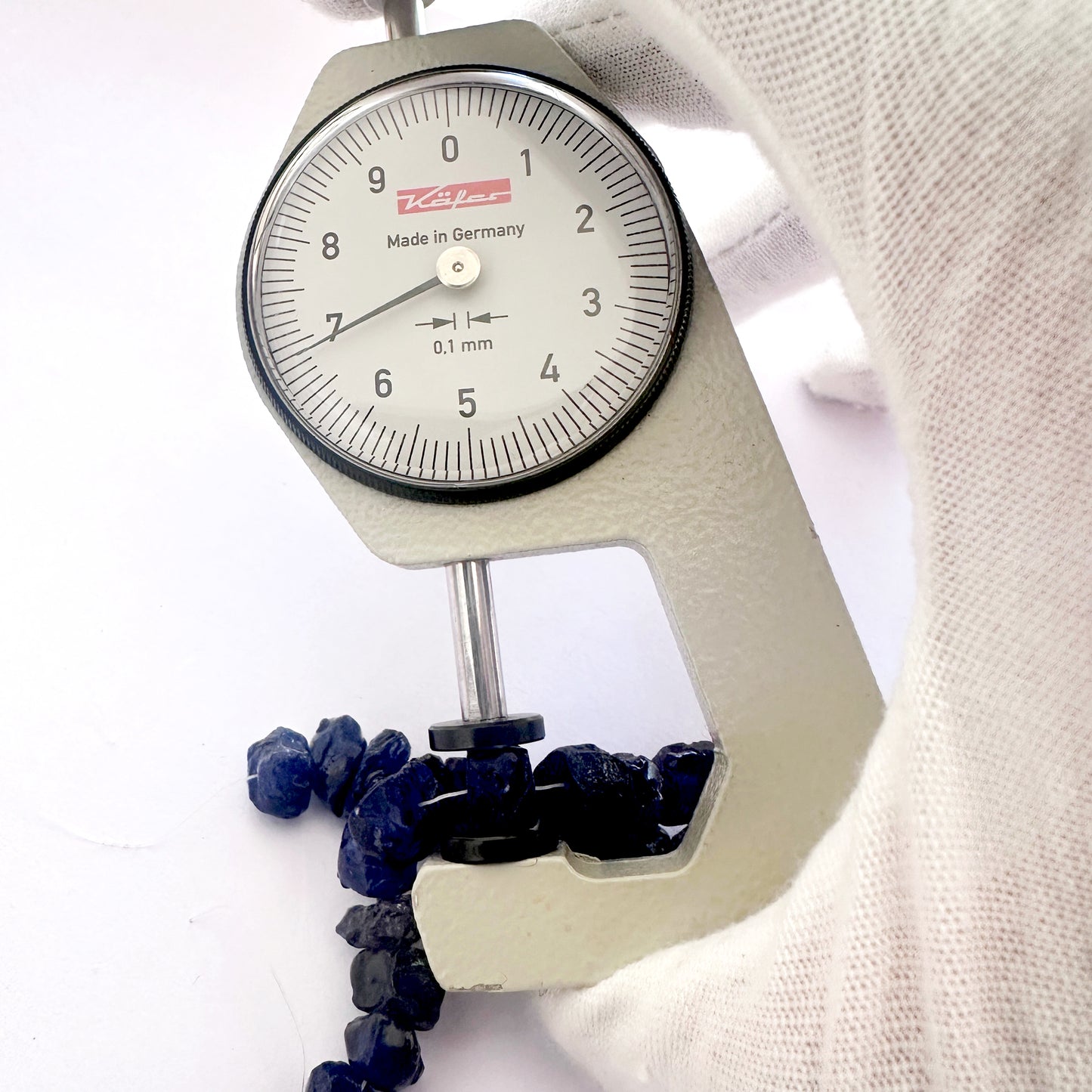 A dial gauge measures the blue sapphire rough centre drilled 8.2–9.5mm gemstone.