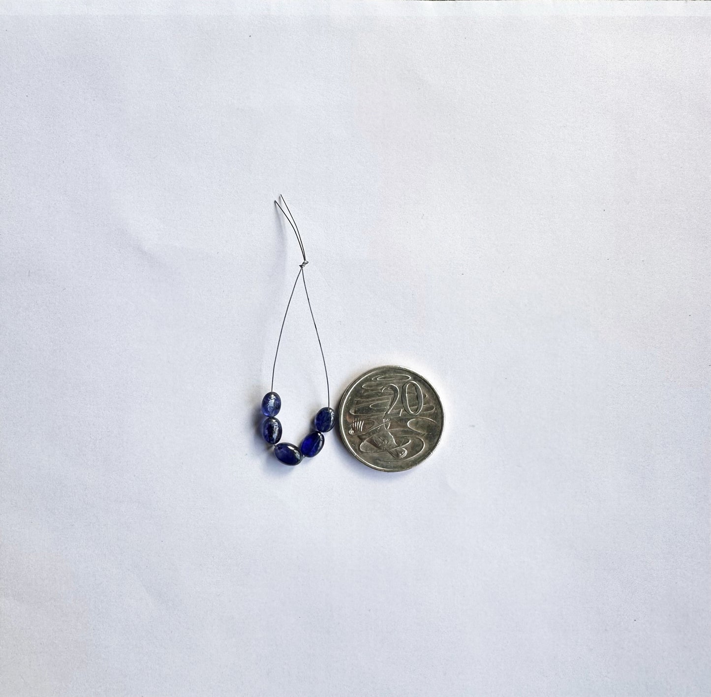 Blue Sapphire gemstone beads shine under soft lighting, enhancing their smooth oval cut and premium clarity.