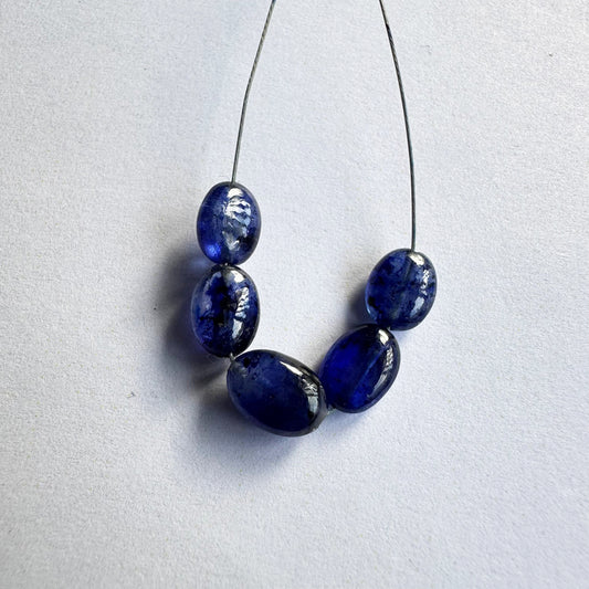Close-up of Blue Sapphire smooth oval gemstone beads reveals their glossy surface and elegant curvature.