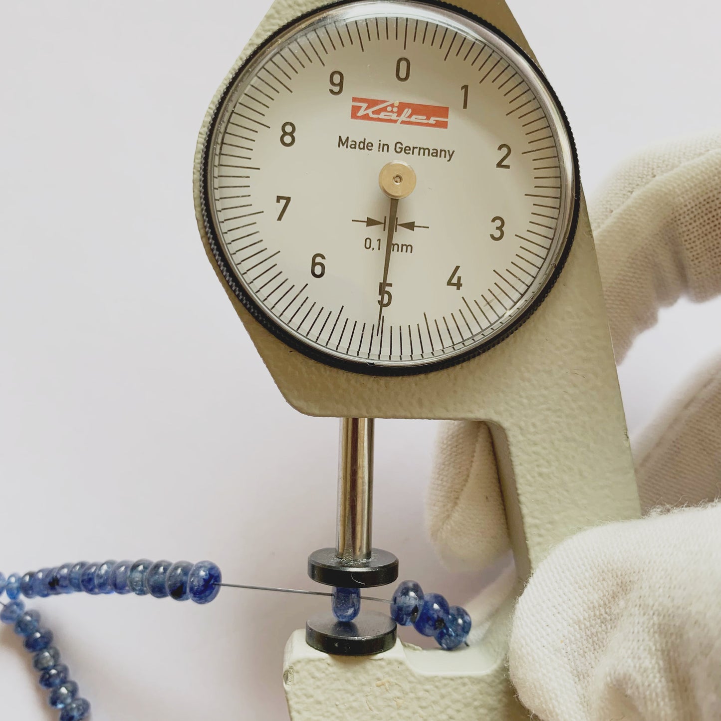 A dial gauge measures the Blue Sapphire rondelle 5.2mm gemstone.