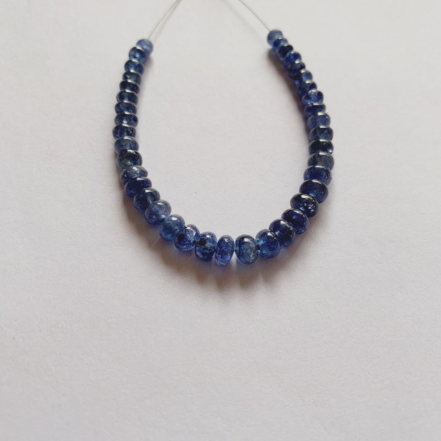 Natural Blue Sapphire beads in graduated sizes, highlighting their rounded cut and luminous blue hue.