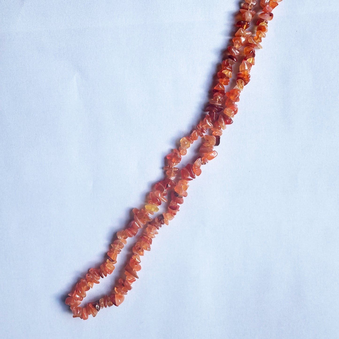 Carnelian chip beads shimmer under soft lighting, enhancing their warm colour variations.