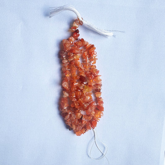 Close-up of Carnelian gemstone beads highlights their raw cut and rich, earthy hues.