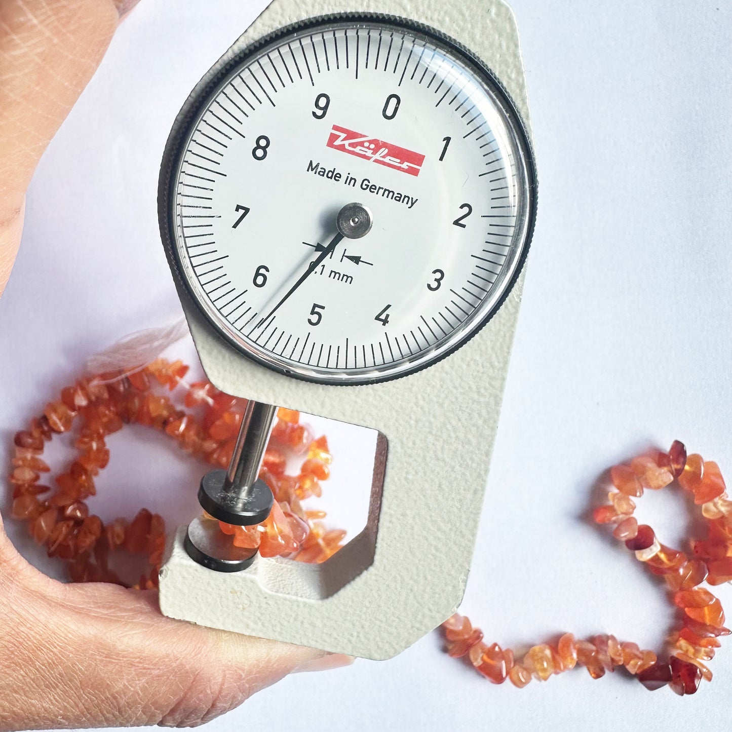 A dial gauge measures the Carnelian chip 5mm to 8mm gemstone, ensuring accuracy in bead sizing.