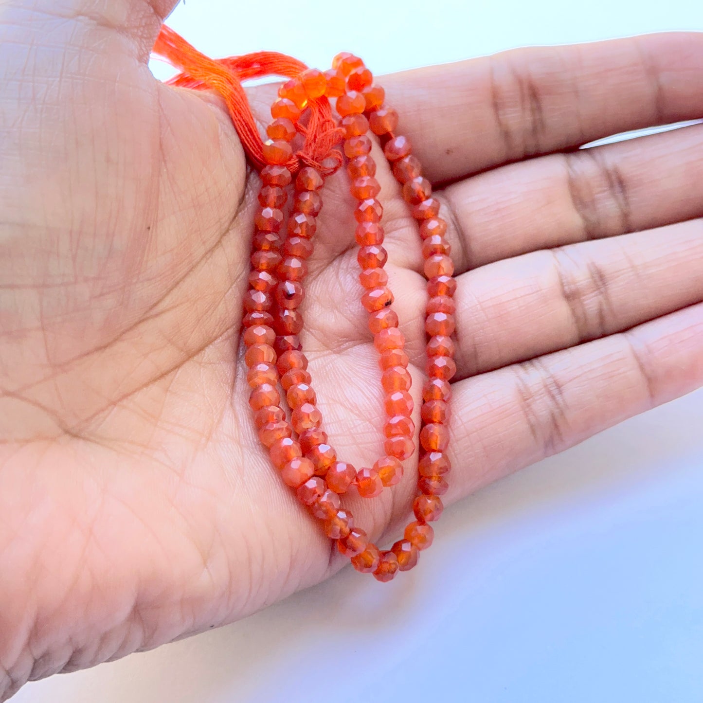 Detailed view of premium Carnelian stone beads showing uniform rondelle shape, deep orange glow and high‑quality faceting.