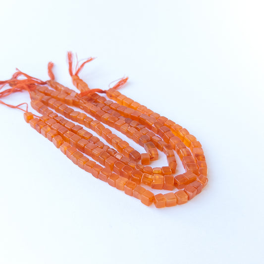 Genuine Carnelian stone beads for DIY jewellery featuring smooth cube shaping and vibrant red‑orange colour.