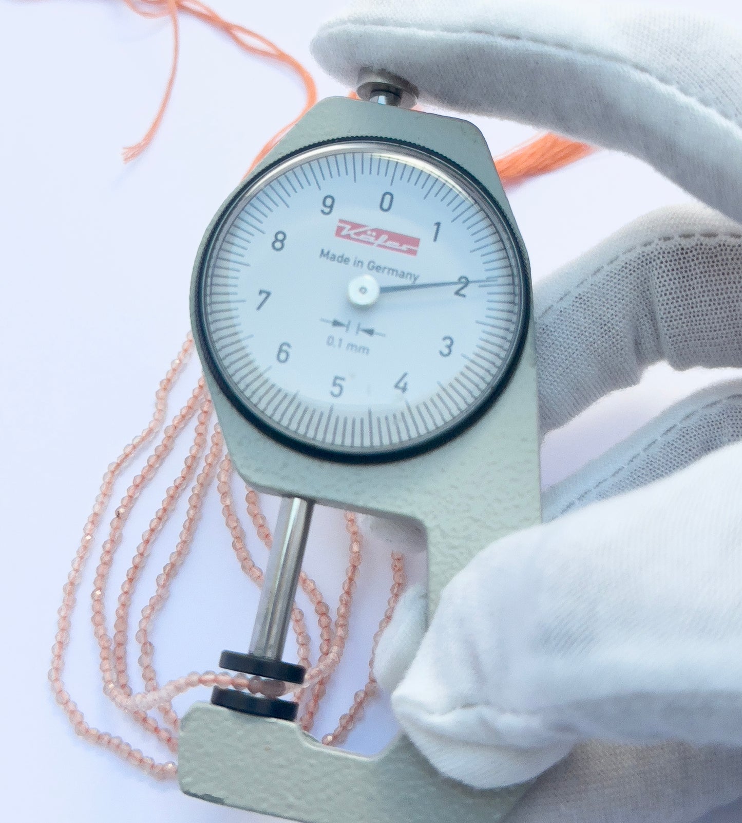 A dial gauge measures the chalcedony faceted rondelle 2mm gemstone.