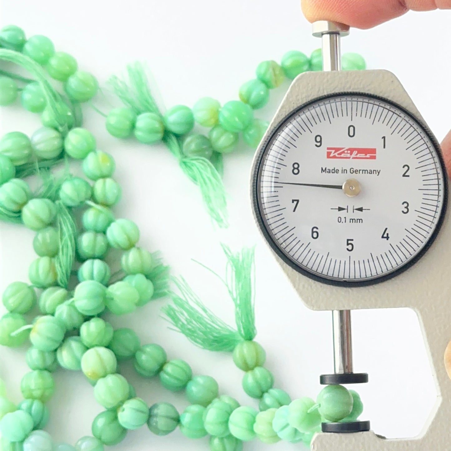 A dial gauge measures textured Chalcedony beads