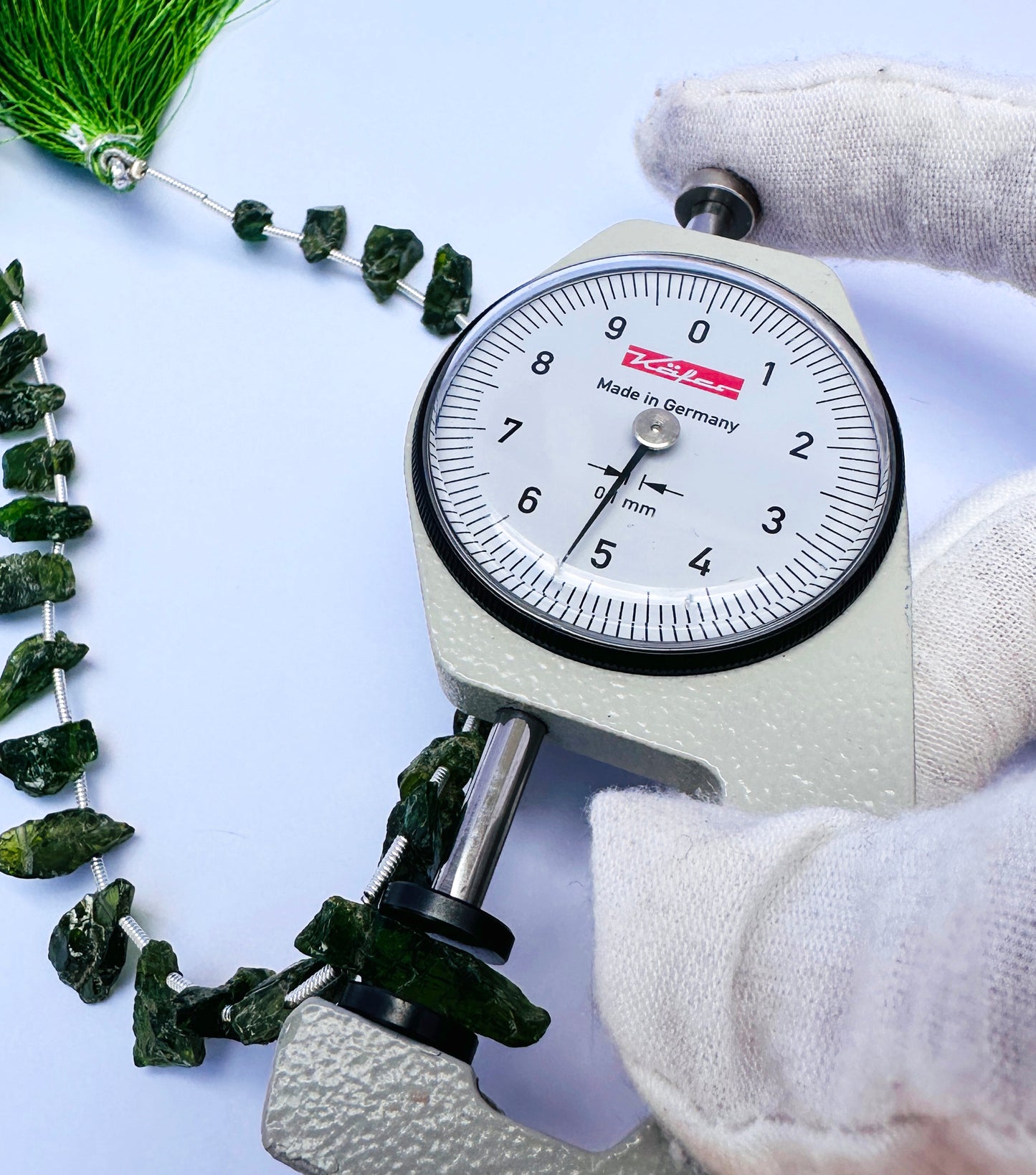 A dial gauge measures the Chrome Diopside rough side drilled gemstone.
