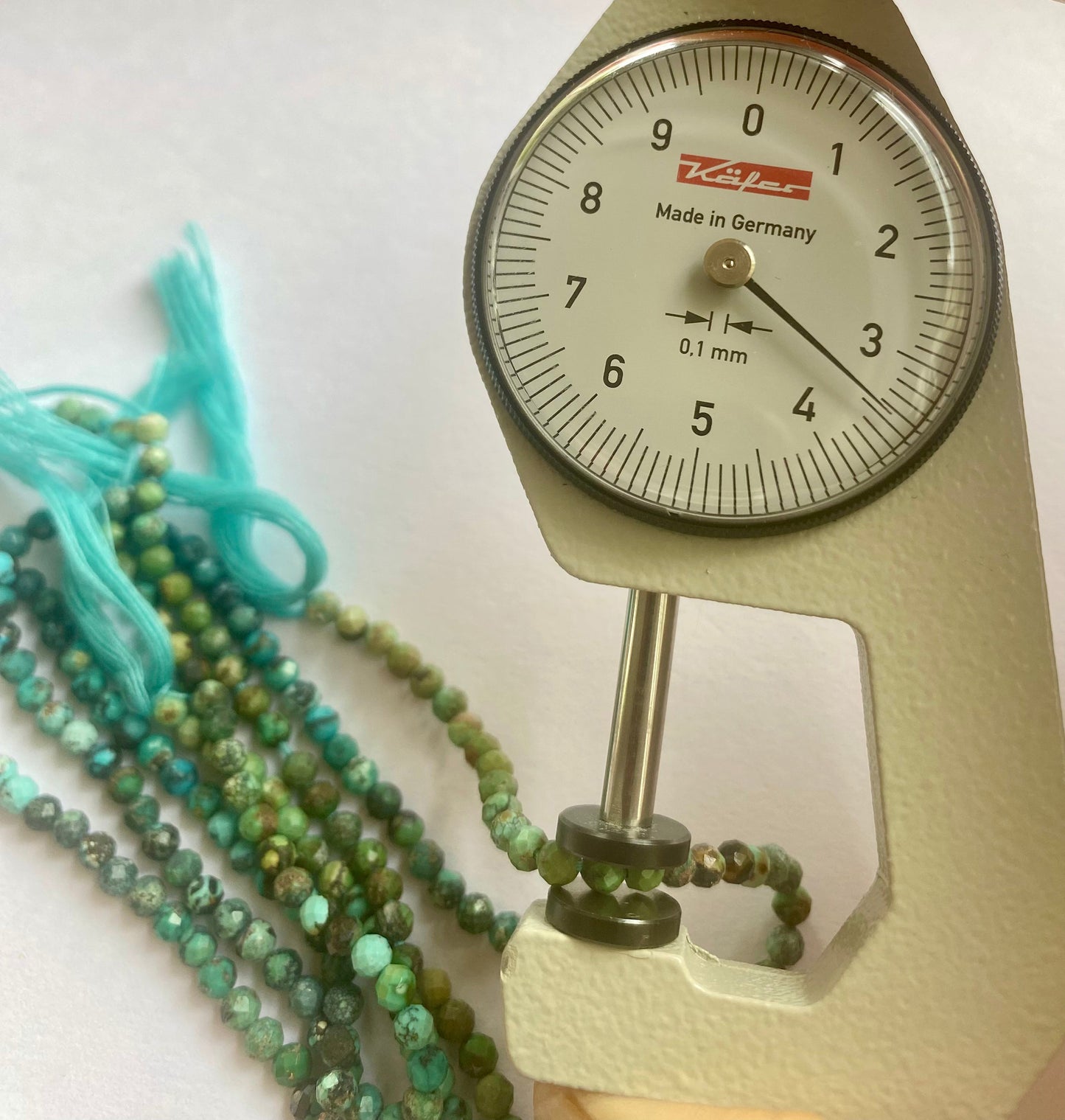A dial gauge measures the Chrysocolla faceted rondelle 3.5mm gemstone.