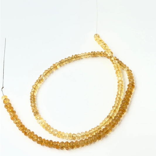 Faceted rondelle Citrine stone beads arranged neatly, highlighting their clarity, shine and handmade jewellery component quality.