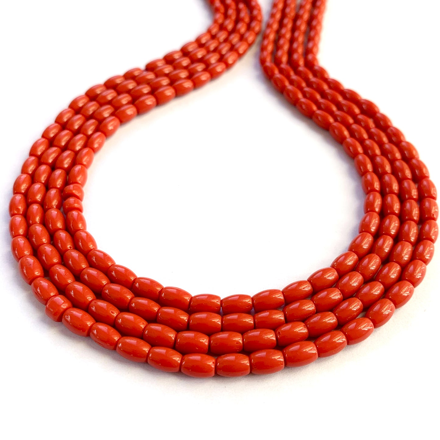 Neatly strung coral beads highlighting their reddish colour and polished surface.
