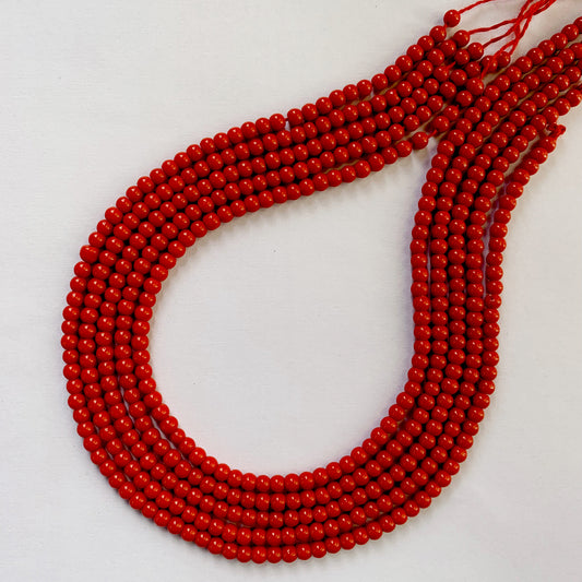 Polished smooth coral beads in radiant red tones strung for jewellery making.