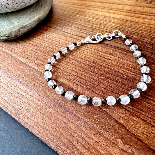 Close-up of crystal and black spinel bracelet featuring polished round stone beads, shimmering contrast and elegant shine.