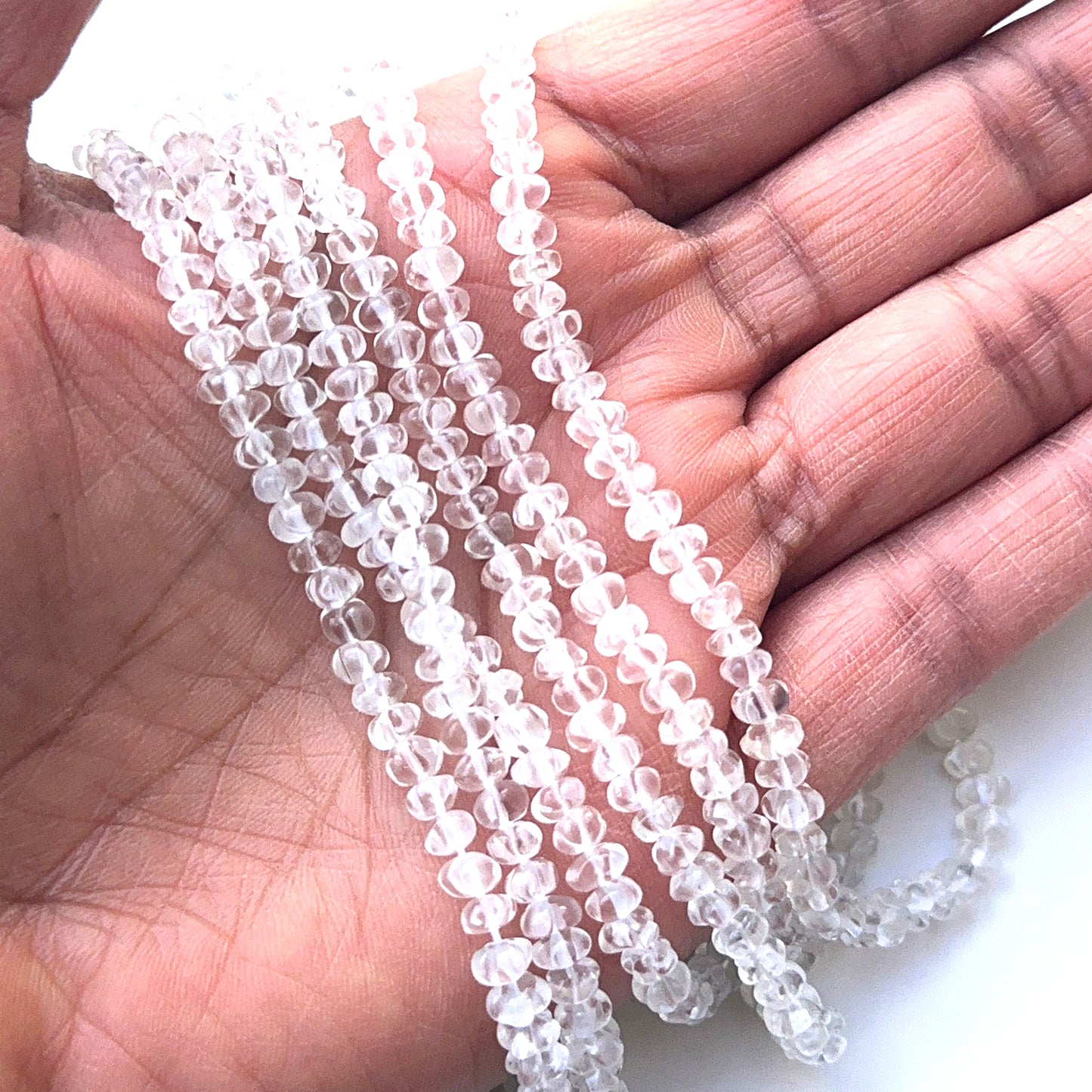 A person holds delicate strands of crystal faceted beads, showcasing their smooth design.