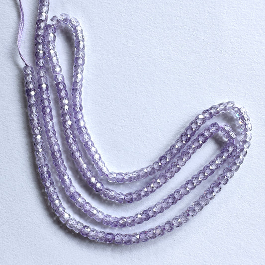 Close-up of synthetic stone beads showing precision-cut facets and consistent round shape.