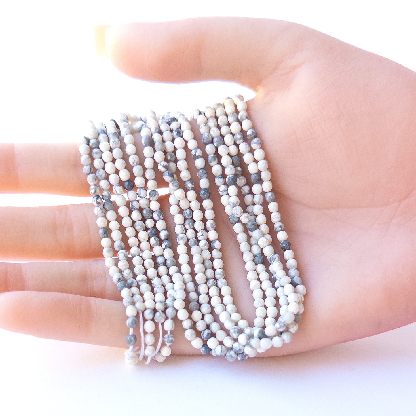 A person holds delicate strands of Dendrite Opal beads, showcasing their faceted rondelle design.