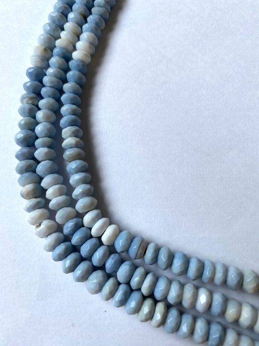 Close-up of Denim Blue Opal beads highlights their expert faceting and striking opalescent glow.