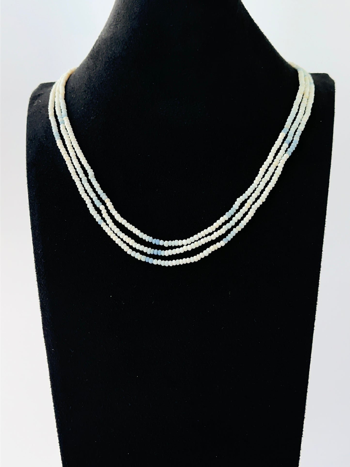 Multi‑strand denim opal necklace with faceted rondelle beads arranged in soft graduated layers.