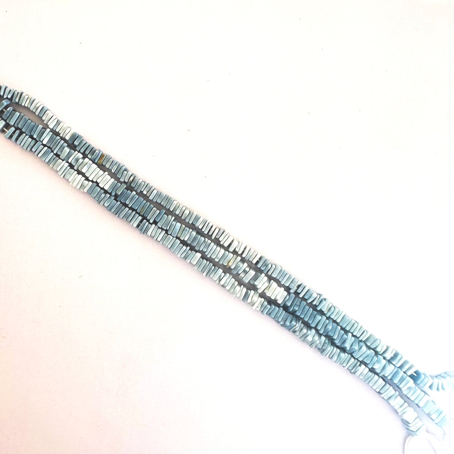 A neat row of Denim Opal Square Heishi beads displaying rich blue tones and sharp geometry.