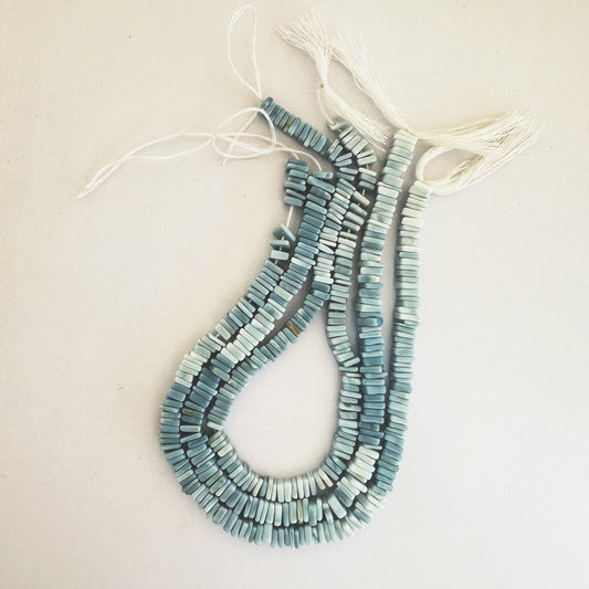 Denim Opal Square Heishi beads neatly aligned on a white background.