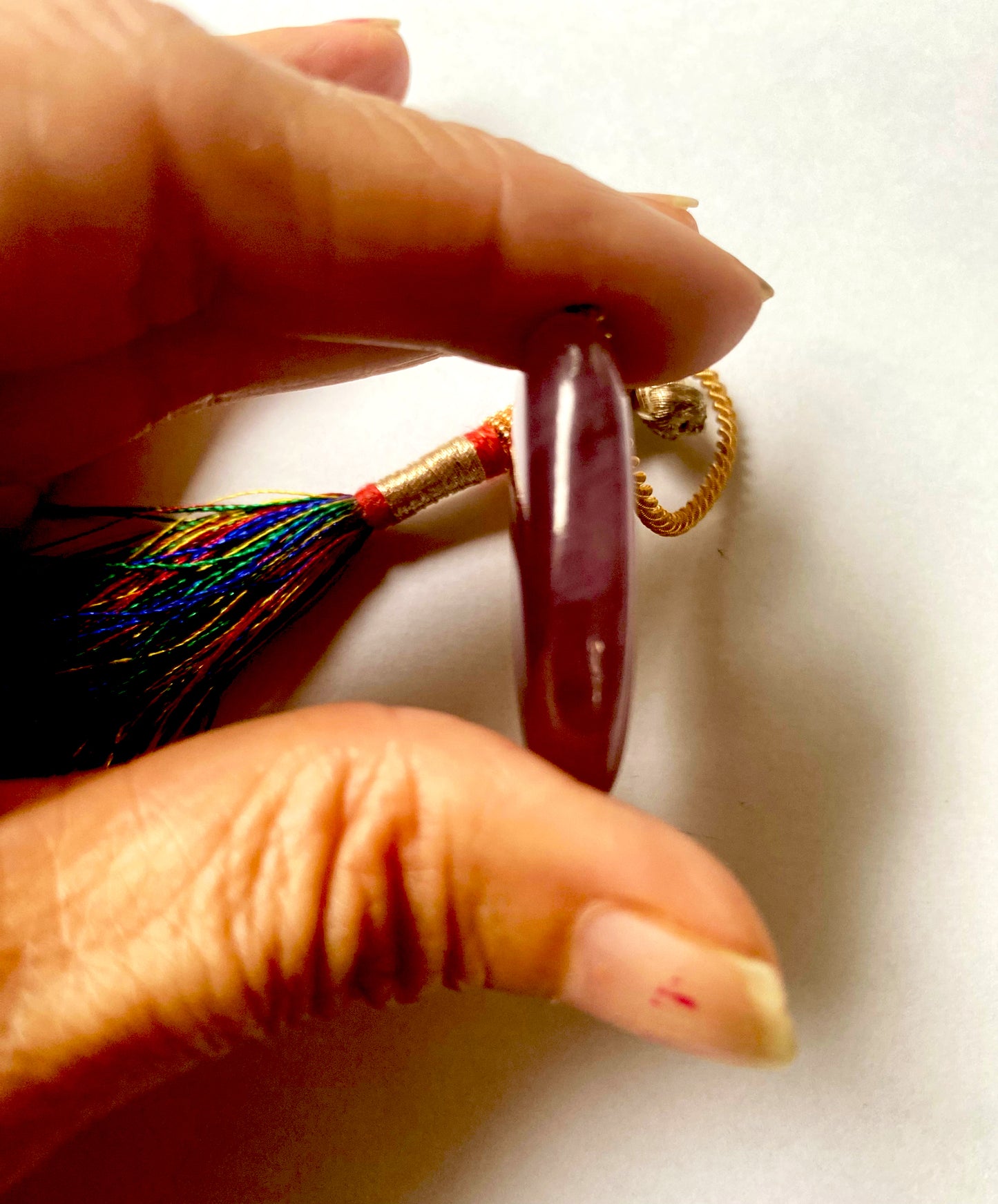 A person holds delicate strands of Ruby beads, showcasing their smooth design.