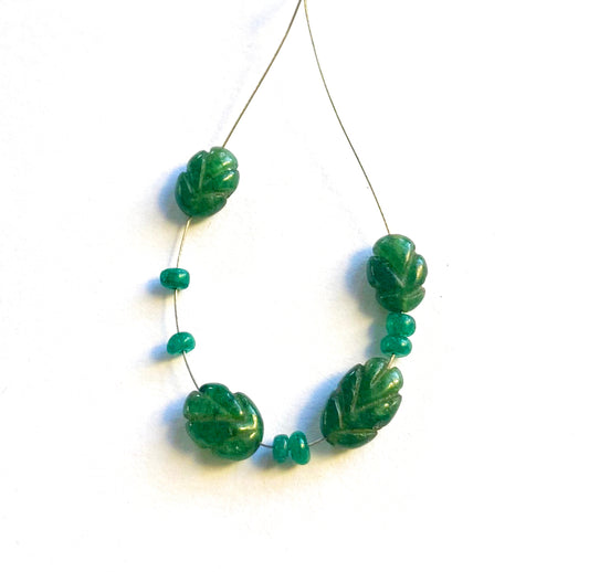 Emerald carved and rondelle gemstones aligned together, showcasing their shape and clarity.