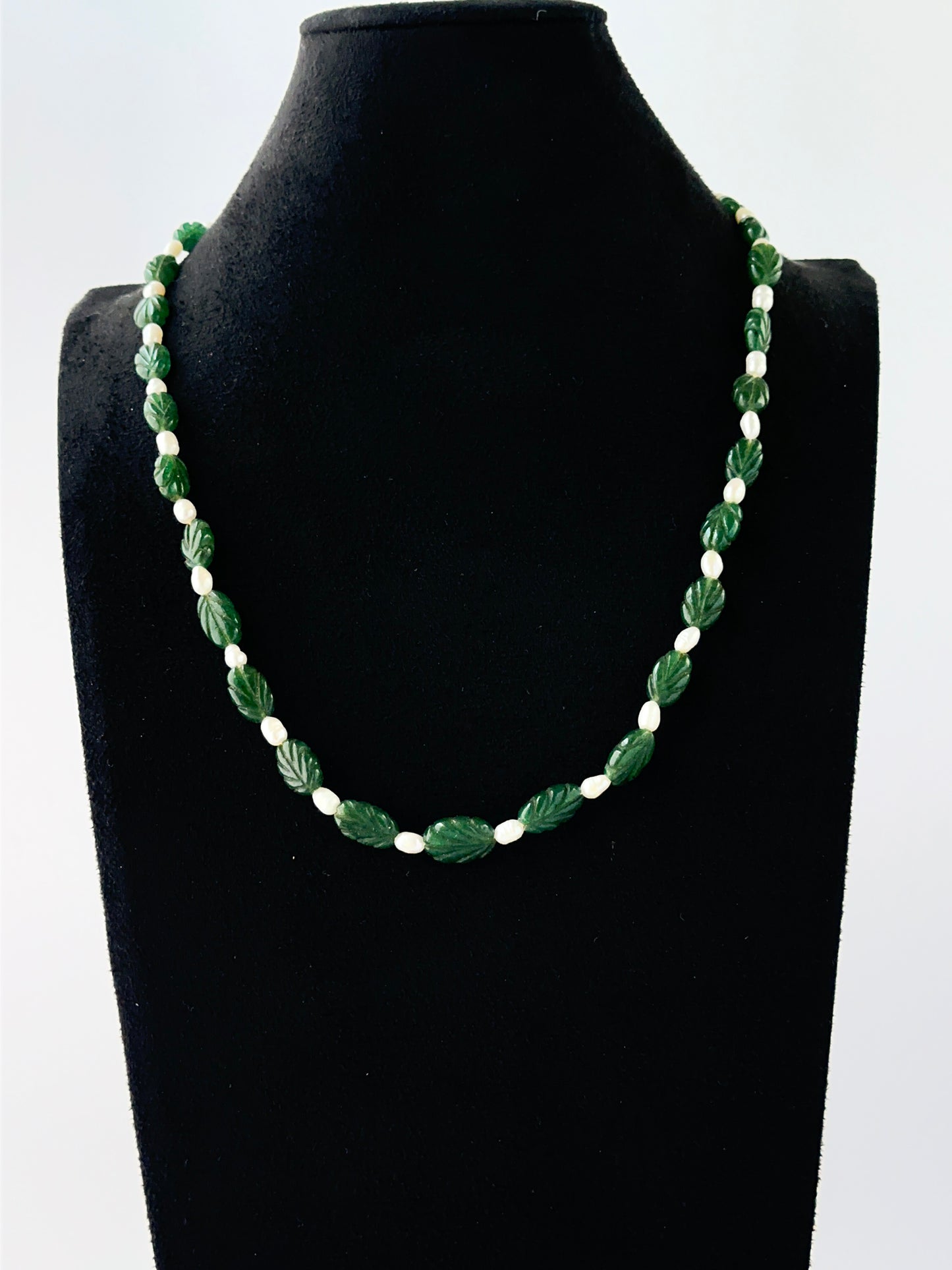 One‑strand emerald necklace showcasing carved oval 8–8.5mm beads in a classic adjustable style.