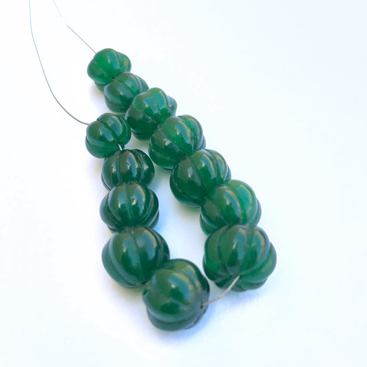 Stone beads showcasing carved pumpkin detailing and vibrant emerald colour.