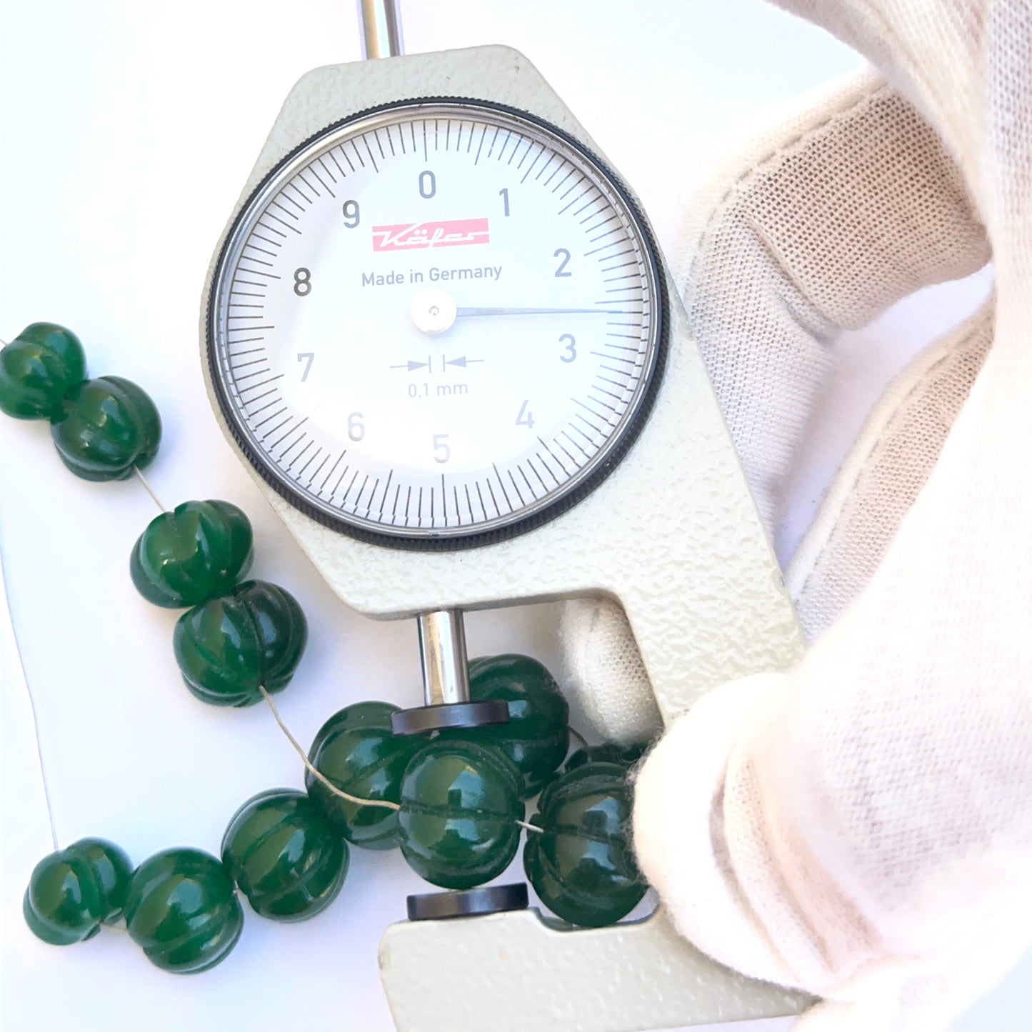 A dial gauge measures the emerald carved pumpkin 9.6–14mm gemstone.