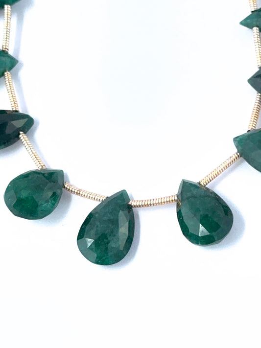 Close‑up of Emerald teardrop stones arranged to highlight clarity and faceted shine.