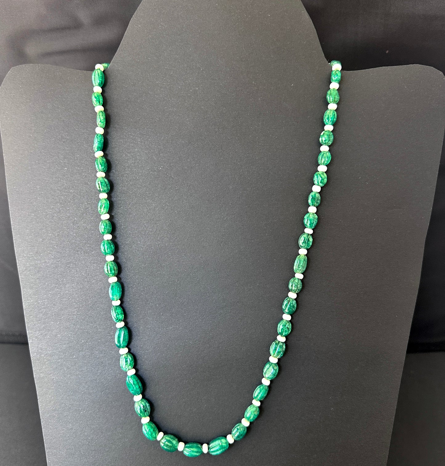 Close-up of carved oval emerald beads, 145 carats, highlighting clarity, polish, and natural gemstone brilliance.