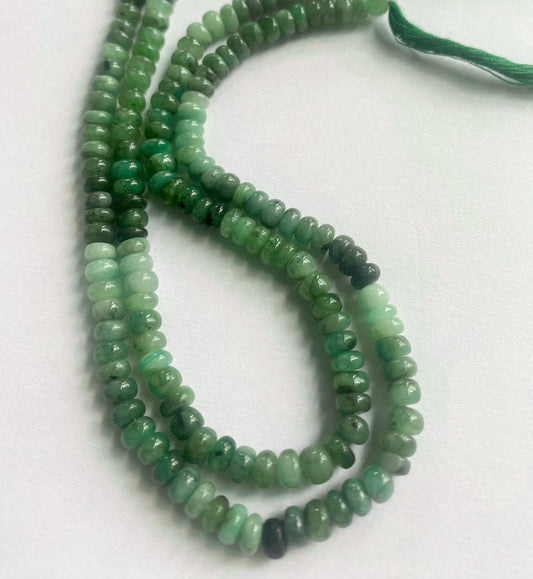 Close-up of emerald gemstone beads showing their polished rondelle cut and natural shine.