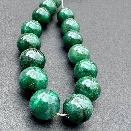 Close-up of emerald gemstone beads arranged in a neat strand showcasing clarity and craftsmanship.