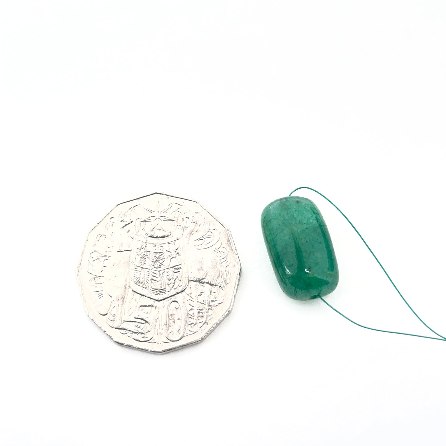 Emerald tumbled drilled stone arranged to highlight gemstone quality and colour depth.