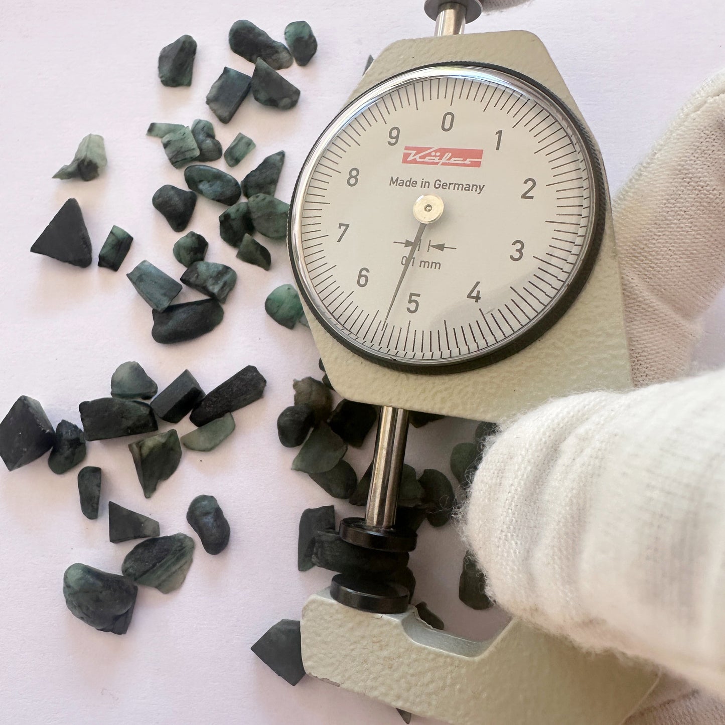 A dial gauge measures the Emerald rough gemstone.