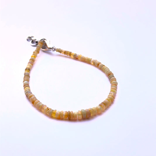 Close‑up of smooth opal rondelle beads arranged on a polished bracelet.