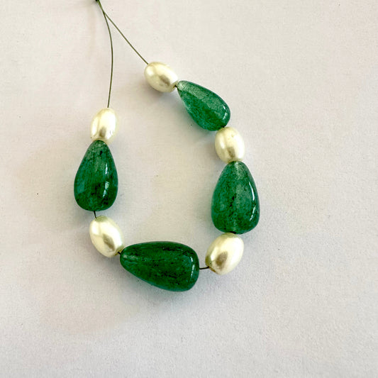 Emerald and pearl beads shimmer under studio lights, showcasing vivid tones and polish.