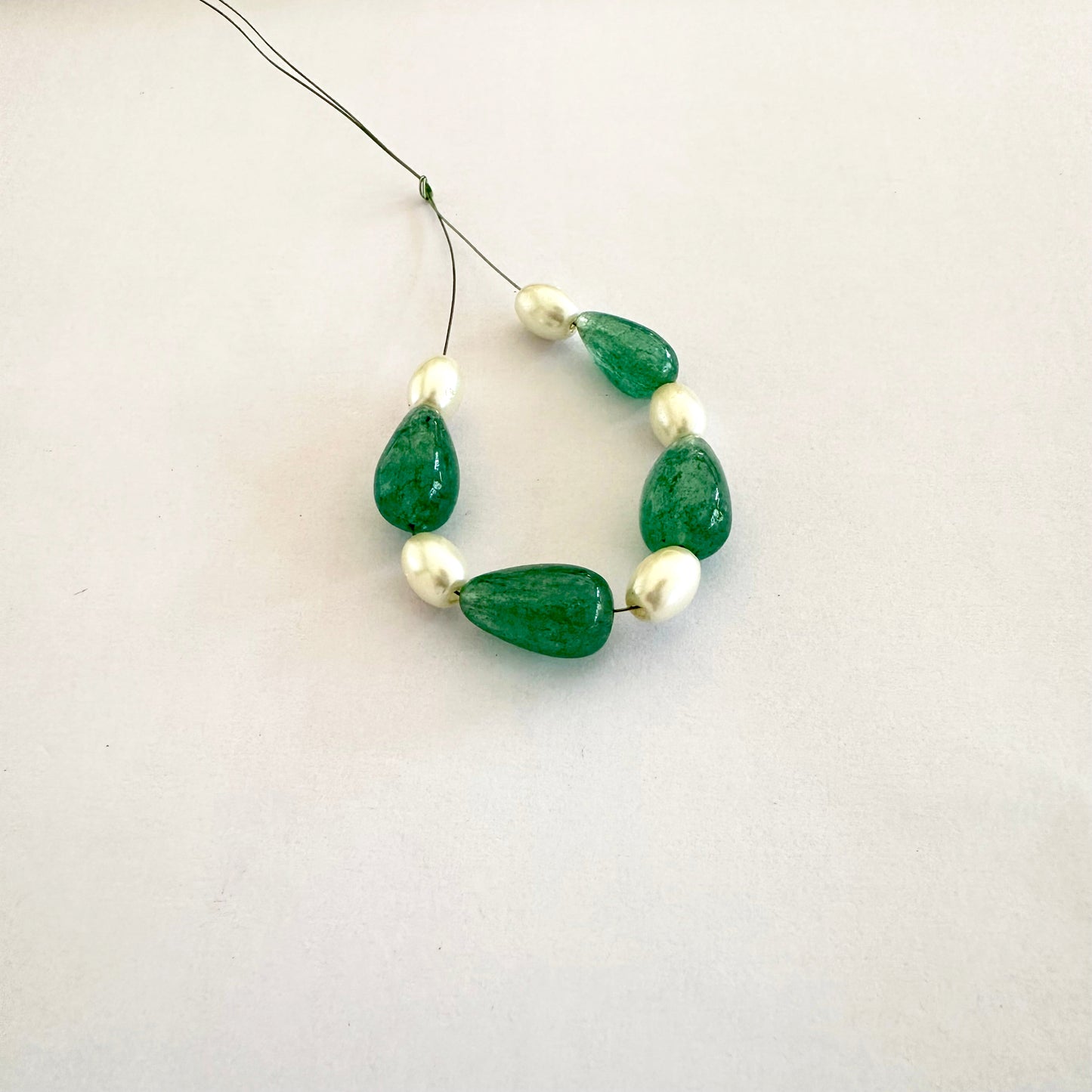 Close-up of glossy emerald beads alongside smooth white pearls in elegant composition.